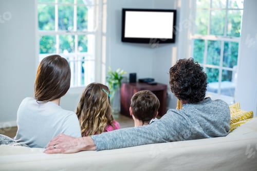 Preview: Family Watching Television While Sitting On Sofa At Home