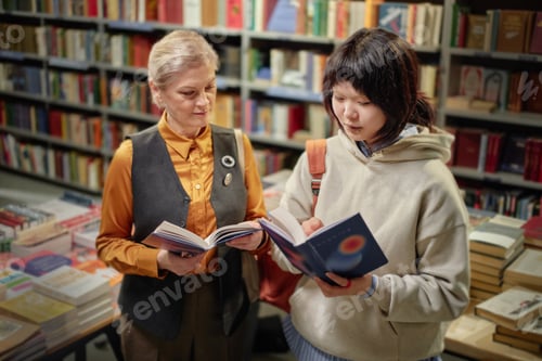 Preview: Middle Aged Caucasian Woman and Young Asian Woman Reading Books in Library