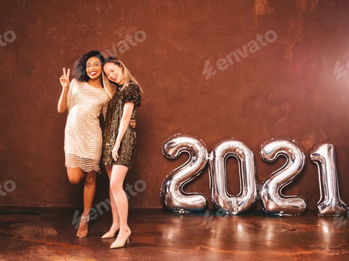 Preview: Portrait of two young stylish women posing in studio near wall