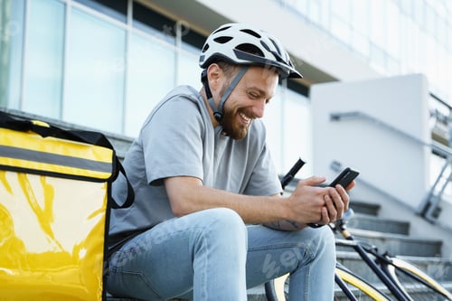 Preview: Express food delivery courier sitting on the stairs with insulated bag and bicycle.