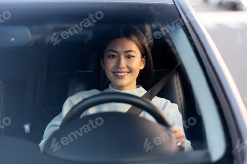 Preview: Asian smiling young woman enjoying driving on a beautiful day
