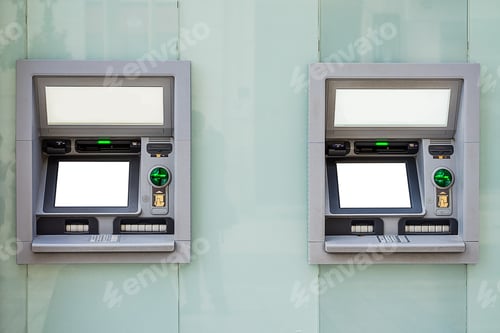 Preview: Isolated shot of two gray atm machines on a light blue wall