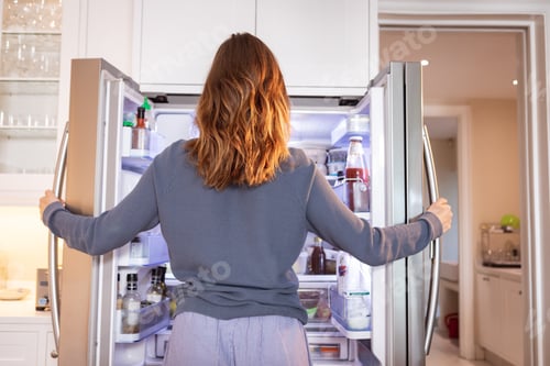Preview: Rear view of woman opening the fridge at home