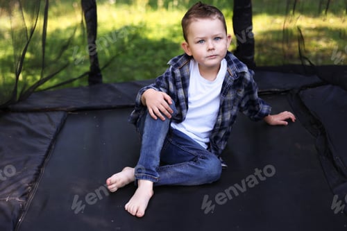 Preview: Cute little boy posing on black trampoline outdoors