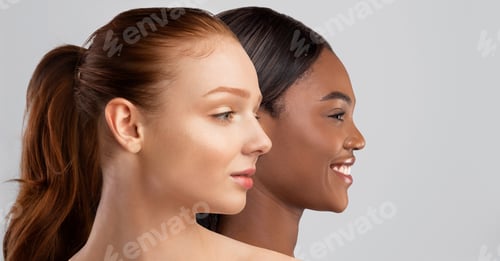 Preview: Black and pale red-haired young women on grey, copy space