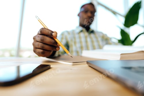 Preview: Serious concentrated african man studying or working with laptop indoors