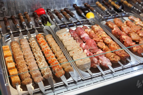Preview: Raw kebabs and meat on metal skewers, ready for grilling, with various types of meat.