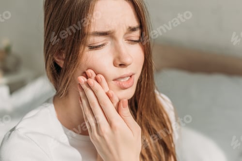 Preview: young woman touching cheek while suffering from toothache