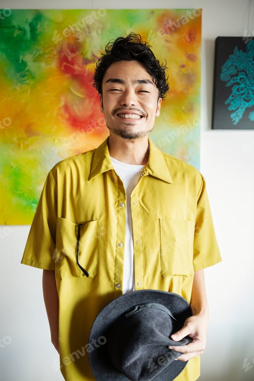 Preview: Japanese man standing in front of abstract painting in an art gallery, smiling at camera.