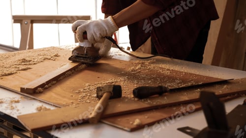 Preview: Carpenter using electric planer to shaving board at site.