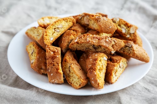 Preview: Homemade Italian Cantuccini with Almonds on a White Plate, side view. Crispy Almond Cookies.
