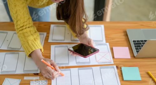 Preview: The young designer is sketching a smartphone screen and an app.