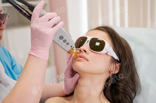 Preview: Therapist cosmetologist makes laser treatment for woman's face in SPA beauty