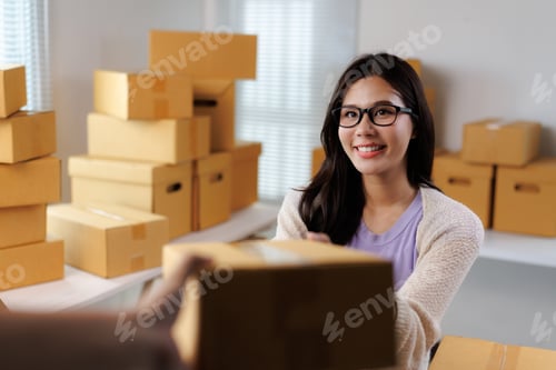 Preview: Young woman running a small business handing a package to a customer
