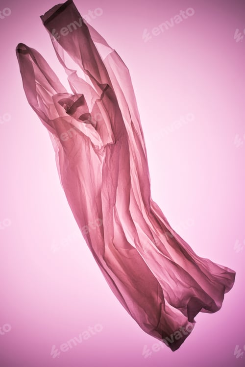 composición con bolsa de plástico transparente arrugada bajo luz de tono rosa