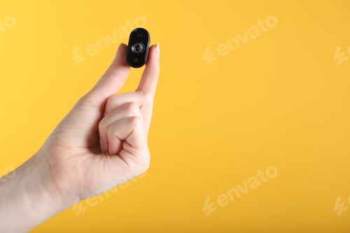 Preview: Woman with hidden spy camera on yellow background, closeup. Space for text