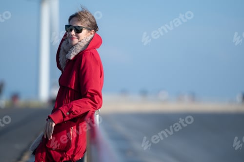 Preview: On the background of windmills, A young woman in a red jacket is enjoying her winter vacation.