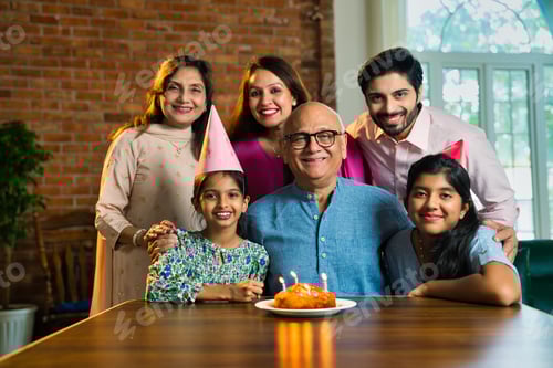 Visualização: Família indiana de seis pessoas comemorando o aniversário do pai idoso com bolo, vela e compartilhando momentos de alegria