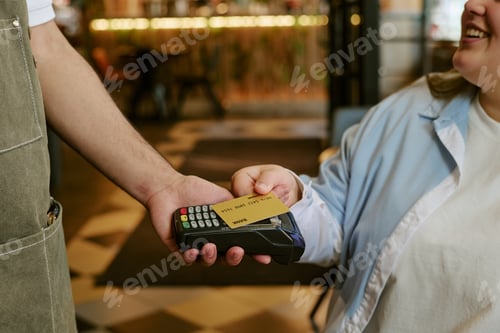 Preview: Young Woman Smiling While Paying with Credit Card at Restaurant