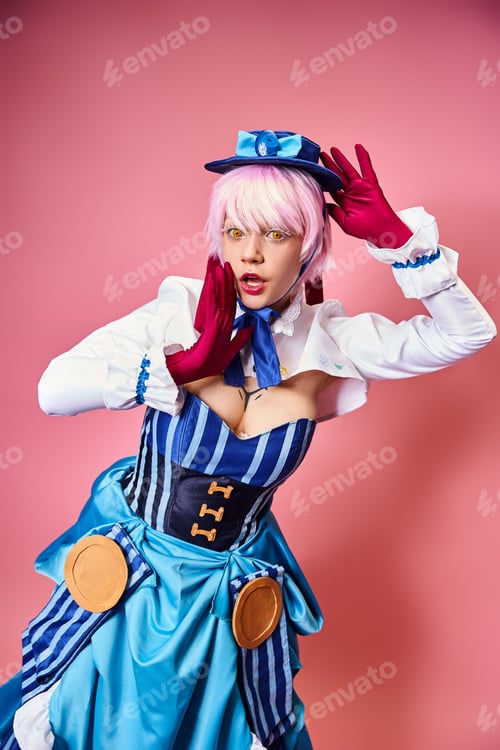 Preview: enticing sexy female cosplayer in blue hat and vibrant attire looking at camera on pink backdrop
