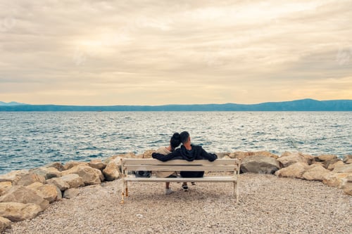 Preview: Couple embracing while seated on a bench overlooking serene adriatic sea with a cloud