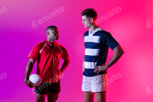 Preview: Diverse male rugby players with rugby ball over pink lighting