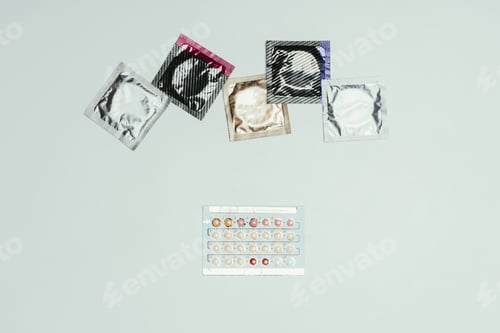 Preview: top view of arranged condoms and contraceptive pills isolated on grey