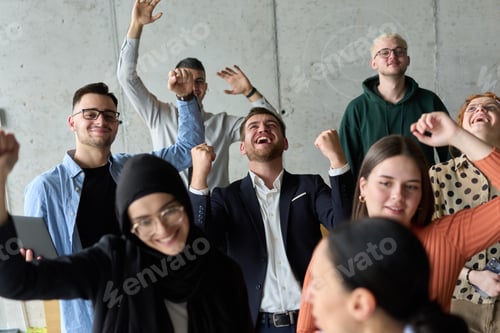 Preview: A diverse team of business professionals ecstatically celebrating their success in a modern office