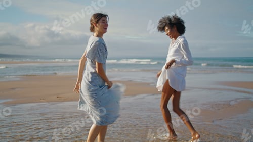 Preview: Happy girls dancing beach on summer weekend. Excited smiling lgbt couple enjoy