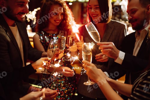 Preview: Glowing sparkles in hands. Group of happy people enjoying party with fireworks. Winter holiday.