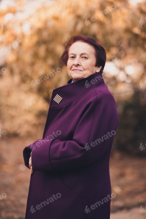 Preview: Senior woman wearing purple autumn jacket stand over nature background close up. Look at camera.