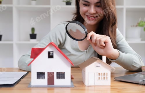 Preview: Happy woman hand holding magnifying glass and looking at house model, house selection, real estate