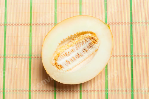 Preview: Sliced honeydew melon on bamboo mat with green lines at noon