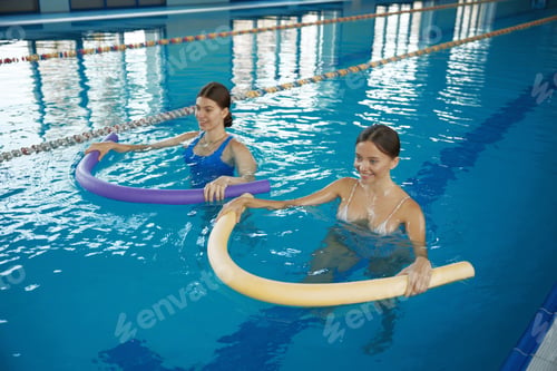 Preview: Two young women training with noodles at swimming pool