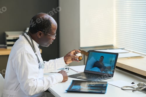 Preview: Mature African American general practitioner recommending pills to patient