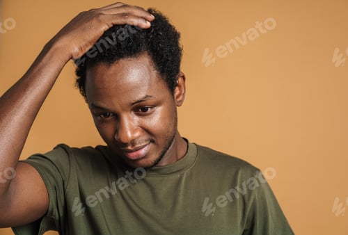Preview: Young black man holding his head and looking downward