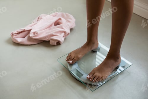 Preview: Low section of woman on bathroom scale at home