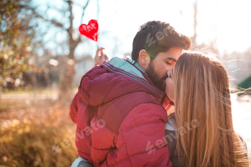 Preview: Stylish couple kissing outdoors.