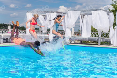 Preview: Group of beautiful young multiethnic people looking happy while jumping into the swimming pool