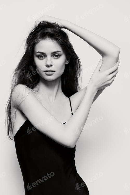 Preview: Elegant young woman with long hair posing confidently in a black dress, showcasing beauty and