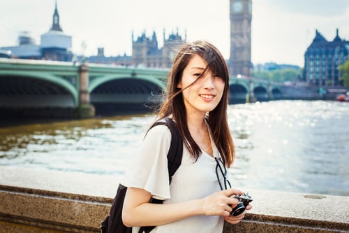 Preview: Young Japanese woman enjoying a day out in London, standing on the Queen's Walk by the River Thames.