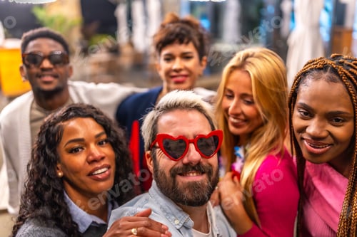 Preview: Man with heat shape sunglasses taking selfie with friends outdoors