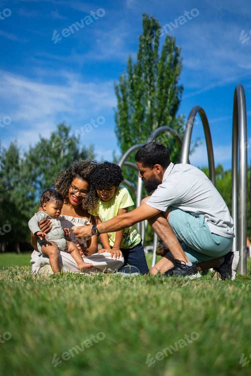 Preview: Venezuelan family of a father, a mother, a child and a baby playing together in a park