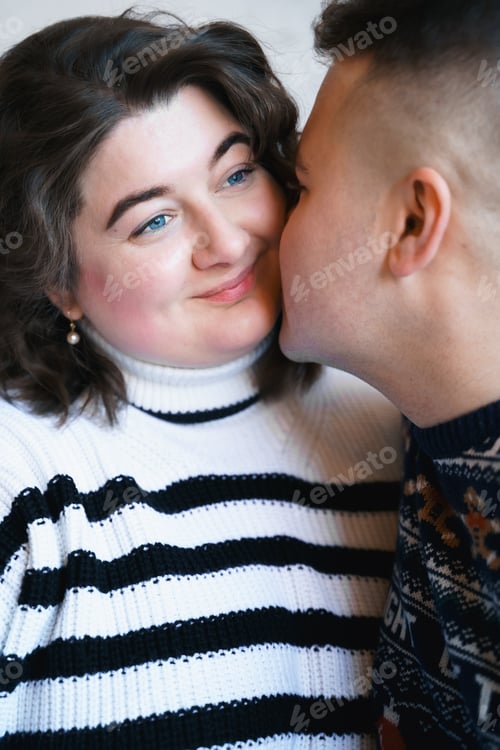 Preview: Loving couple in cozy sweaters. Sweet love moment lovestory. Body positive plus-size smiling woman.