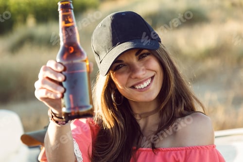Preview: Beautiful young woman drinking beer and enjoying summer day.