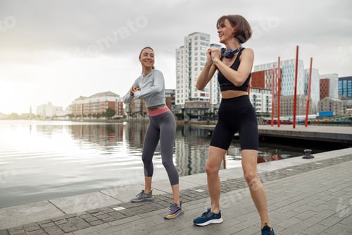 Preview: Beautiful sportive women doing fitness exercise on city background at morning
