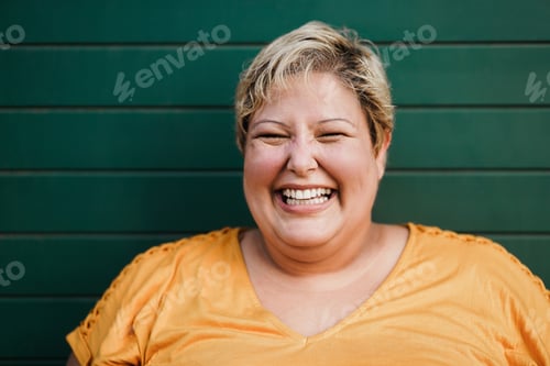 Preview: Portrait of curvy woman smiling on camera outdoors with green background - Focus on face