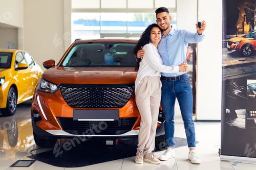 Visualização: Casal feliz do Oriente Médio mostrando a chave, comprando um carro novo