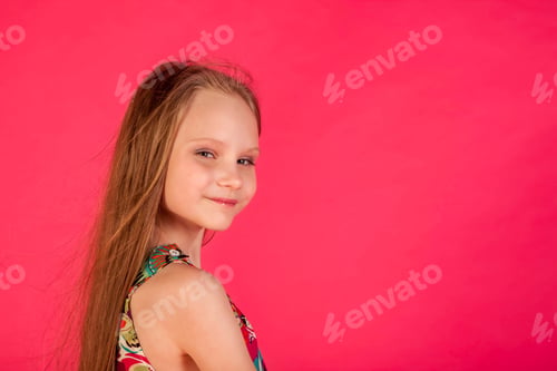 Preview: Portrait of smiling little girl in colorful t-shirt posing at pink background