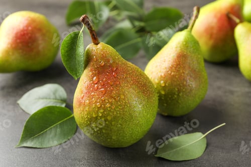 Preview: Fresh ripe pears and green leaves on grey table, closeup